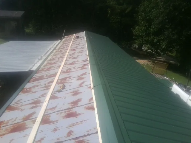 Old rusted panels beside newly installed green metal roofing — Wind Damage Roof Repair by Roofing Brothers in Latah