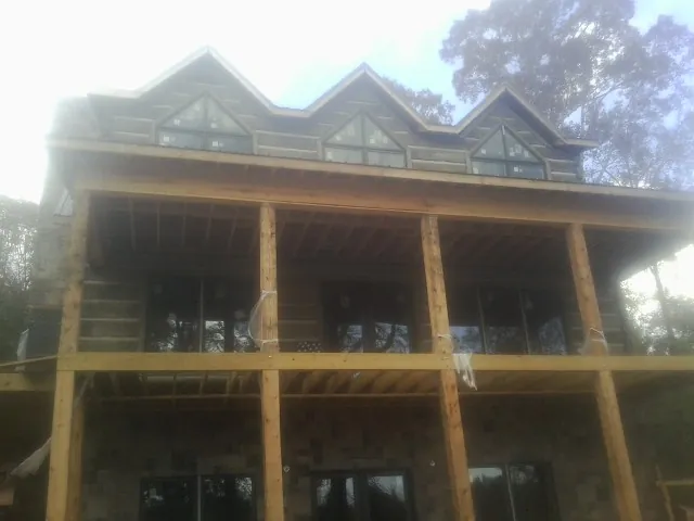 Dormers and porch framing on a large log home under construction — Roof Coating work by our crew in Latah
