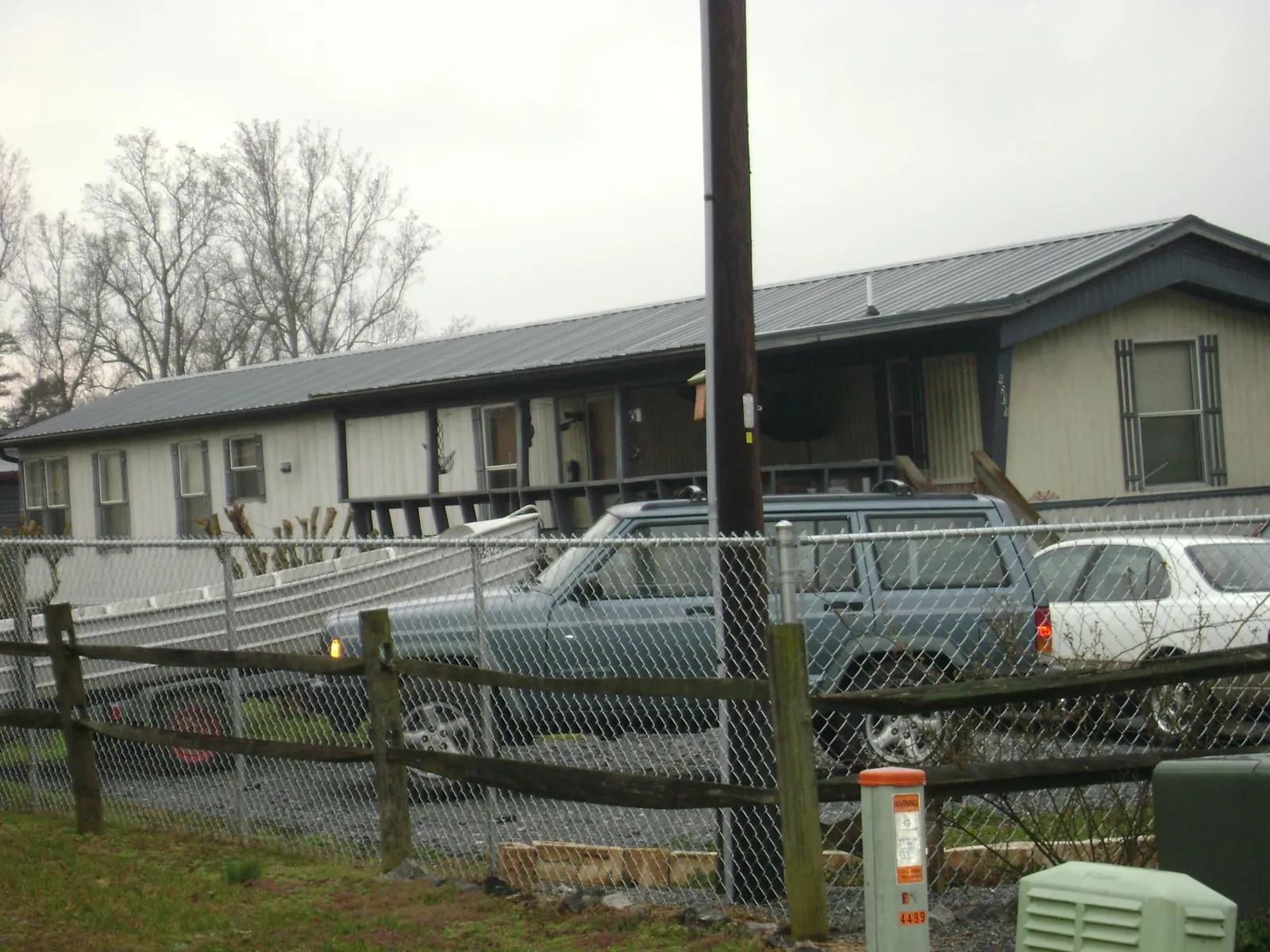 Dark metal roof on a long single story building behind a chain link fence in Latah