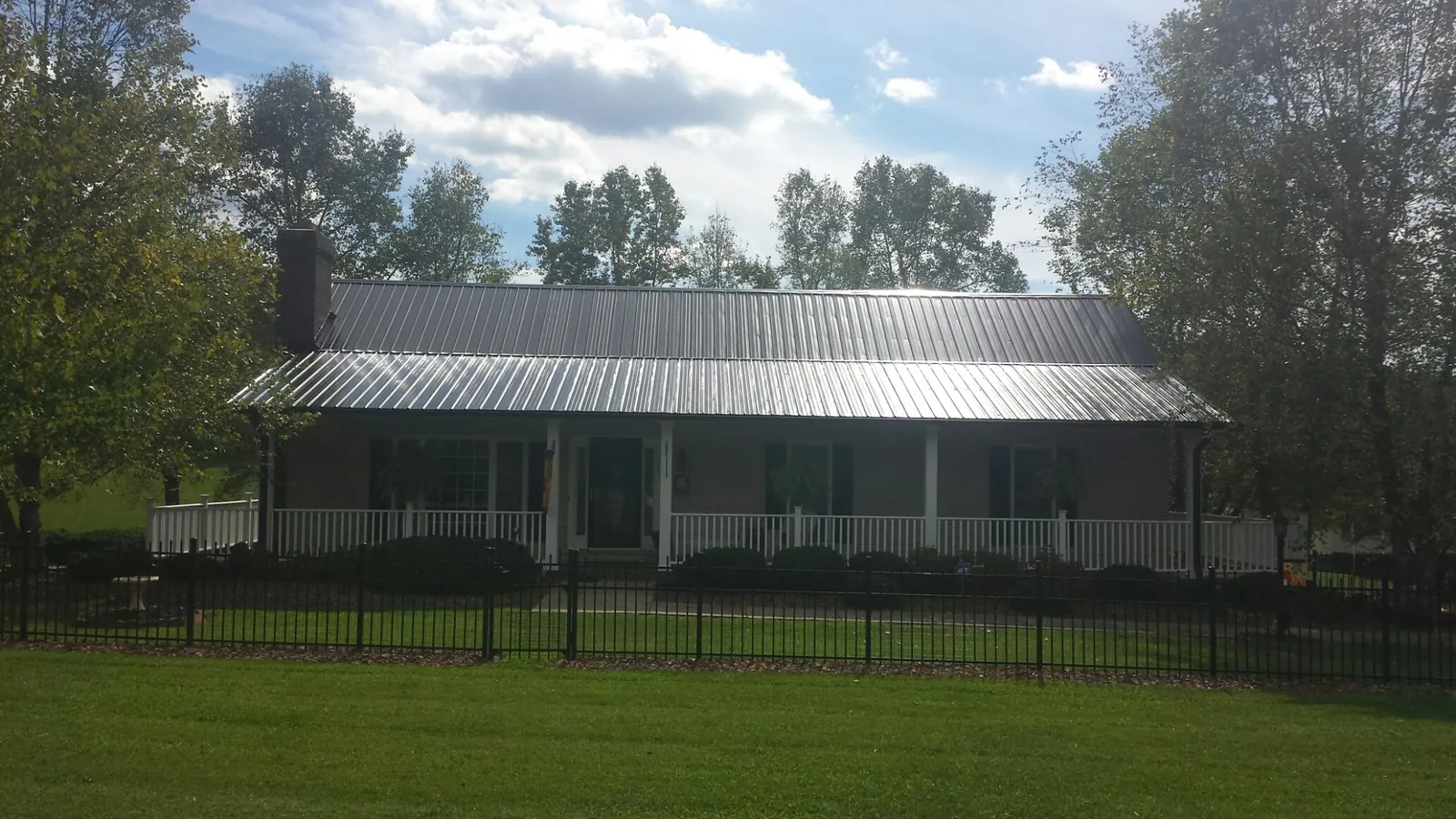 Gray metal roof on a brick ranch with a full width front porch — Gutter Guard Installation work by our crew in Latah