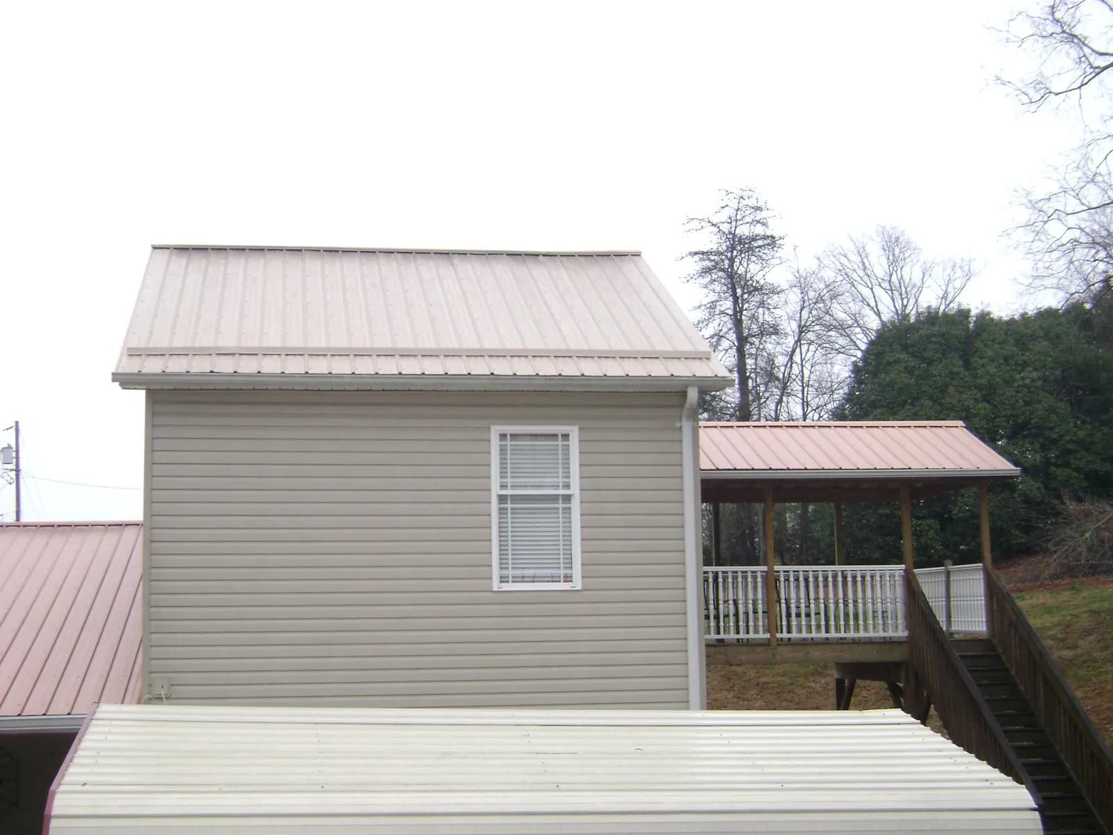 Tan metal roofs on a two story addition and attached porch, from a Roof Replacement job in Latah