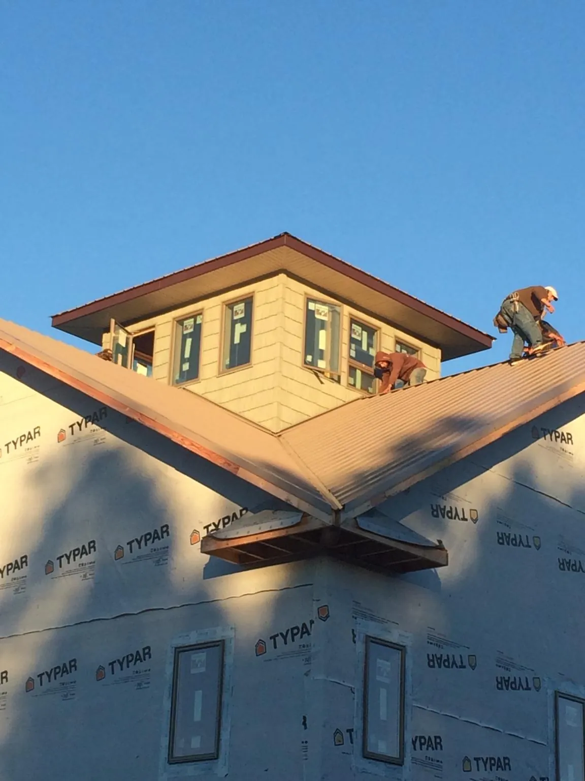Roofers working around a rooftop cupola on a new metal roof at sunset — Roof Waterproofing in Latah by Roofing Brothers